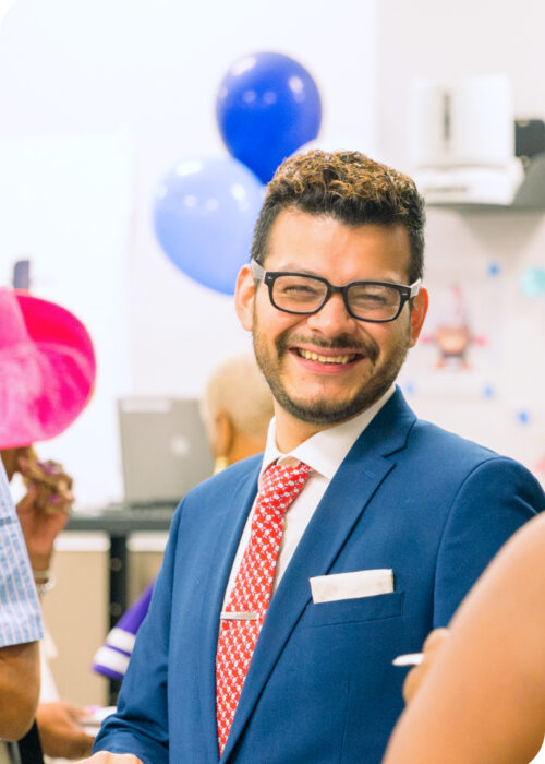 A photo of a man with glasses smiling at a career fair.