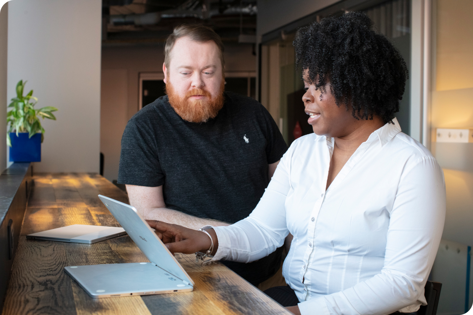 A Merit America learner working with a coach at a laptop
