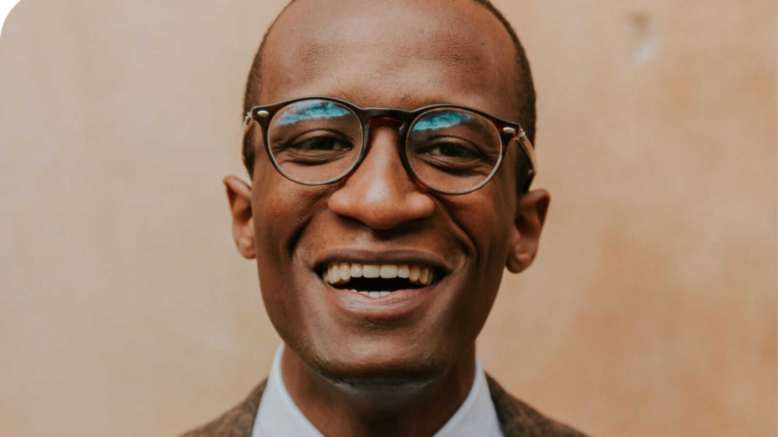 A headshot of a bald man with glasses smiling.