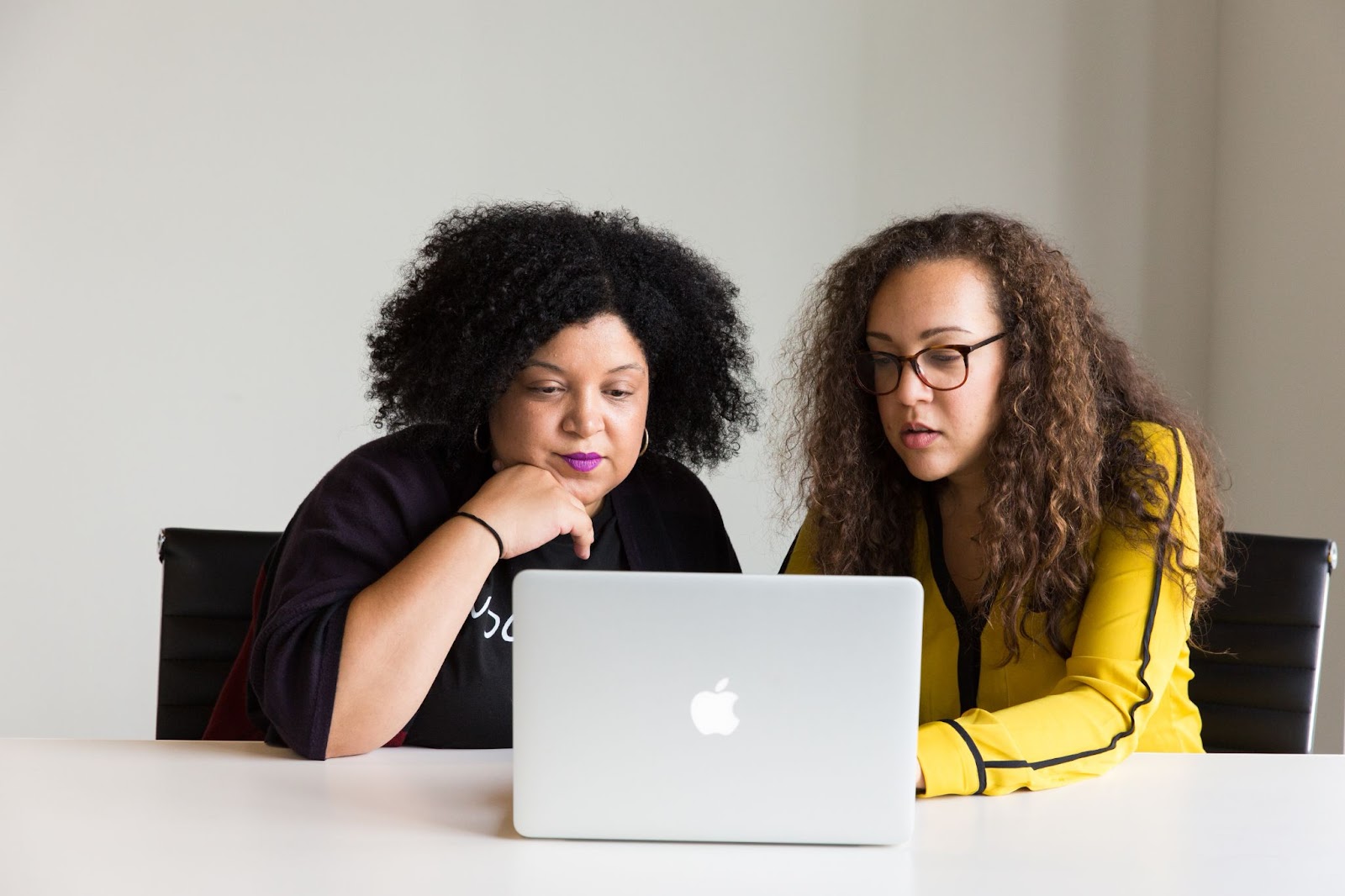 Two women in an office working on improving UX designer skills through a UX design course
