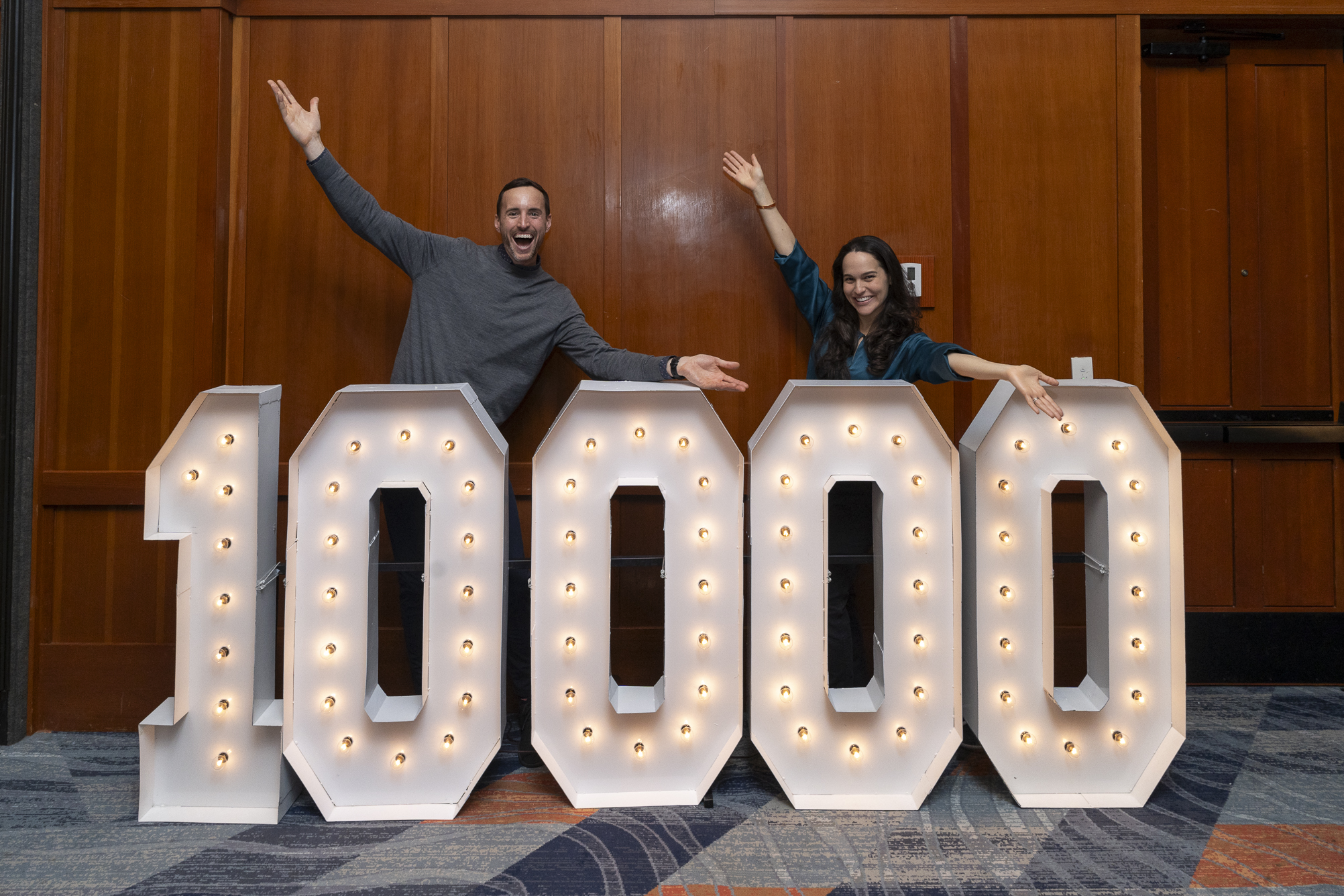 Merit America Co-CEOs standing behind a 10,000 learner sign.