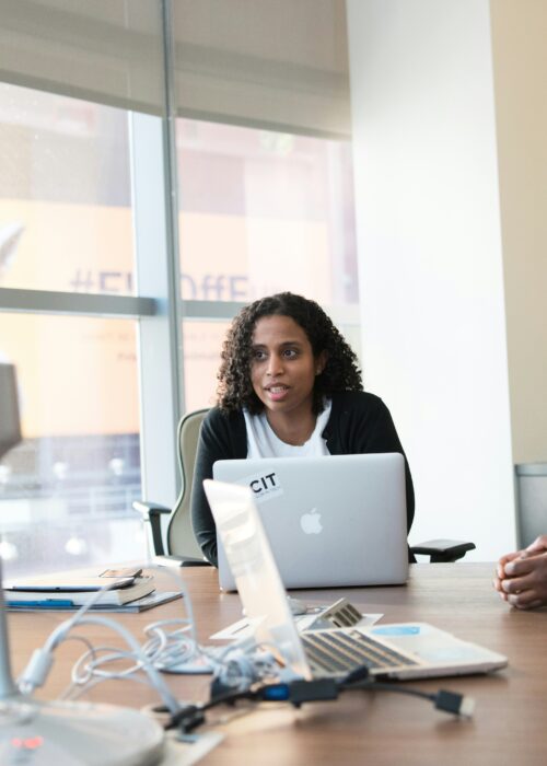 Three women in a conference room discussing solutions to their company's problems.