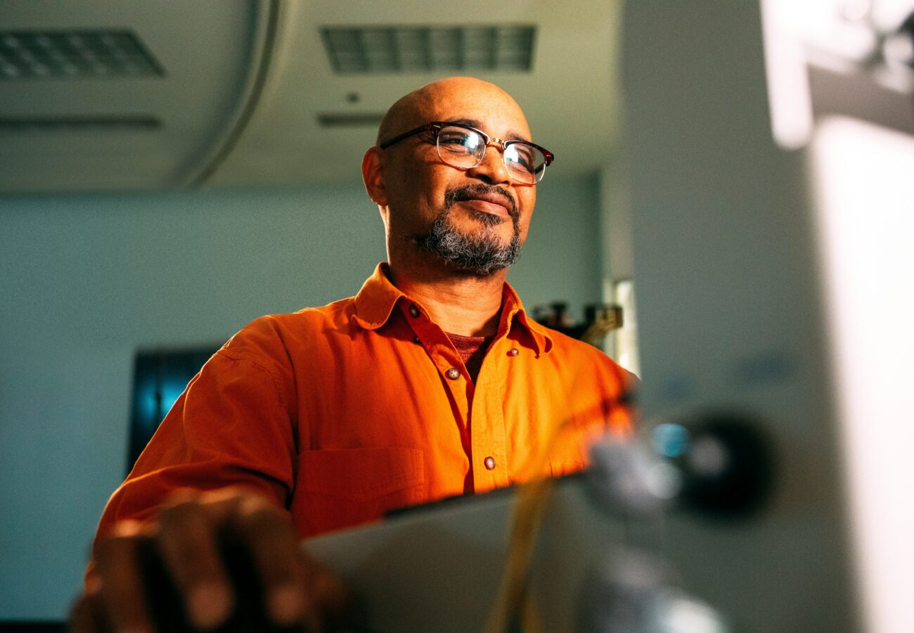 A man in glasses standing at a computer.