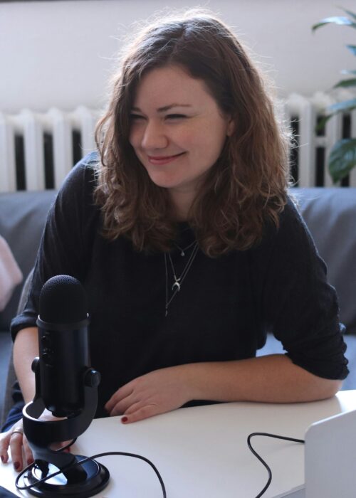 A woman smiles behind a microphone.