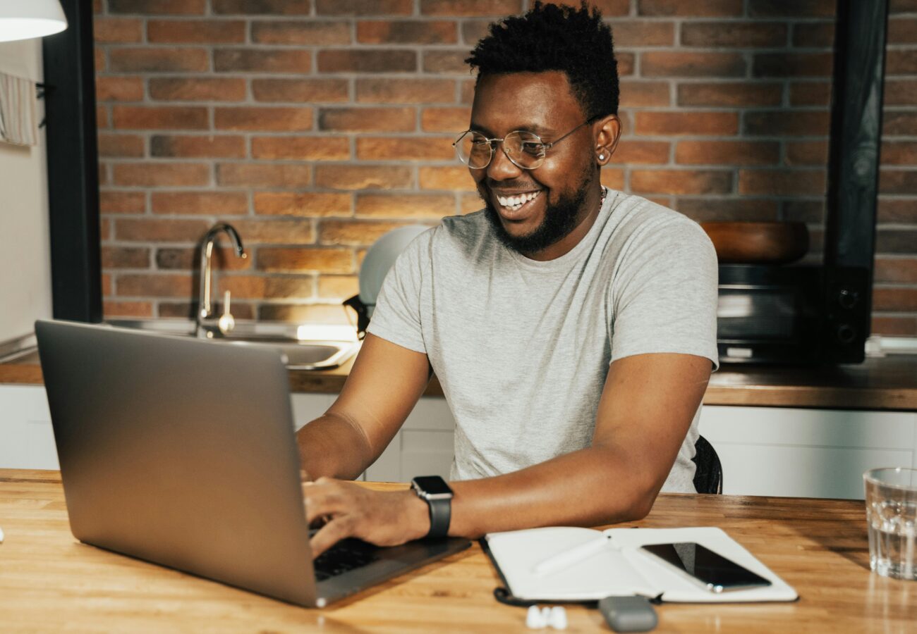 A man smiling on a laptop.