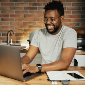 A man smiling on a laptop.