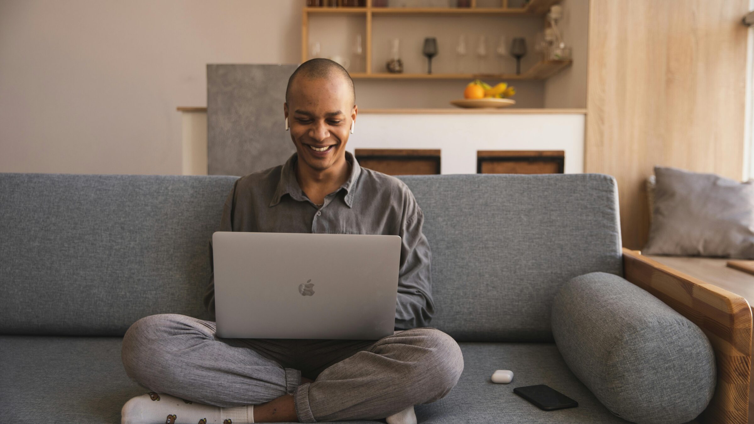 A man sits on the couch cross legged
