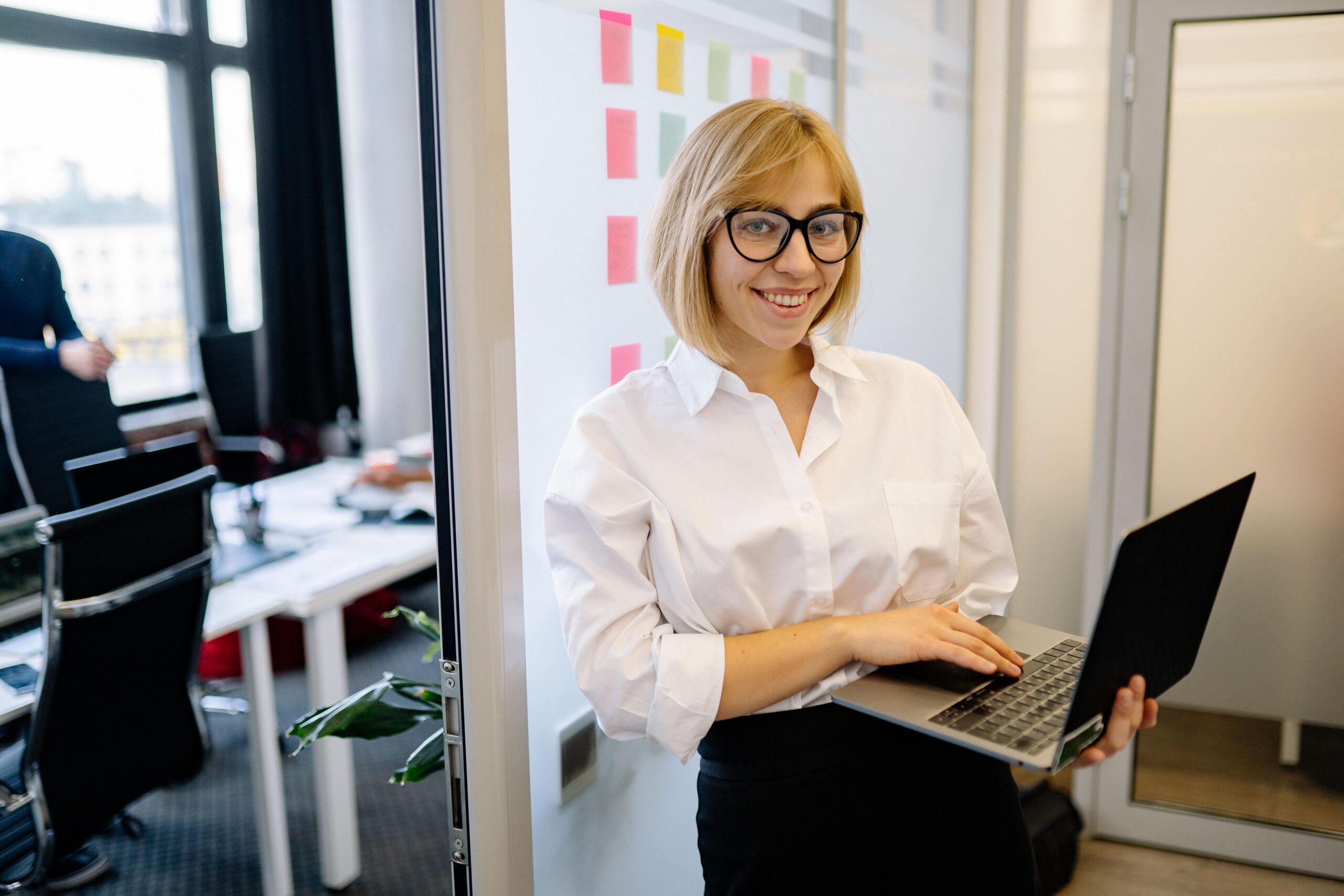 A person standing with a laptop in a bright office